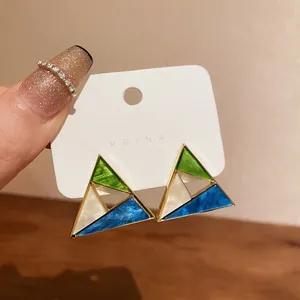 Macro view of geometric triangle earrings with green white and blue enamel detail