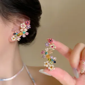 Dettaglio orecchini a fiore colorati e ear cuff con cristalli multicolori vivaci