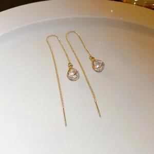 Detailed macro view of elegant gold threader earrings with clear teardrop crystal drops