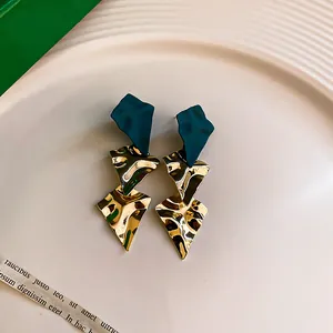 Detail view of oversized geometric drop earrings with green and gold textured finish