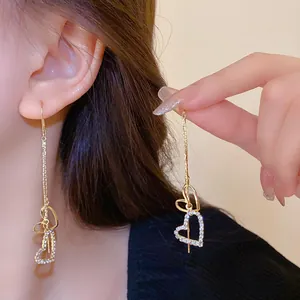 Close-up detail of elegant long heart tassel earrings with sparkling rhinestones.