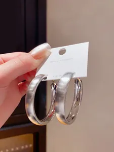 Primo piano di grandi orecchini a cerchio in argento spazzolato con perni in argento S925.