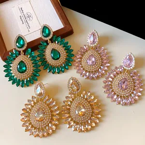Detailed view of oversized flower earrings with teardrop crystals in green and pink.