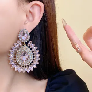 Detailed close-up of exaggerated teardrop flower earrings featuring pink rhinestones