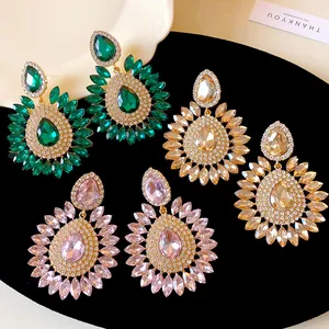 Detailed view of exaggerated crystal flower drop earrings in green, gold, and pink colors