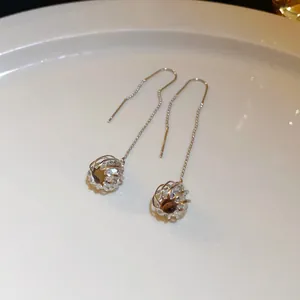 Detailed macro shot of long silver tassel ear line earrings with spherical cage charms
