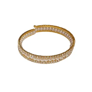 Elegante bracciale a tre strati con perle e strass scintillanti, finitura dorata.