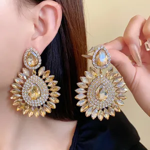 Macro view of luxury oversized champagne crystal sunflower statement earrings on model