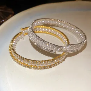 Vista dettagliata di eleganti bracciali a tre strati con cristalli e perle lucenti.