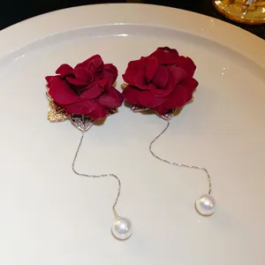 Elegant detailed view of red fabric rose earrings with long silver tassels and pearls