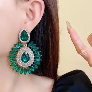 Macro shot of exaggerated green crystal floral drop earrings with rhinestones