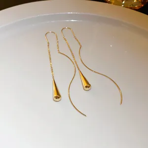 Close-up detail of elegant gold-toned long tassel ear lines with polished teardrop pendants