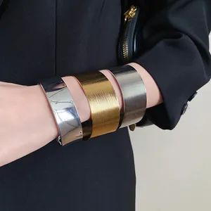 Close-up of textured stainless steel wide cuff bangles in silver and gold finishes