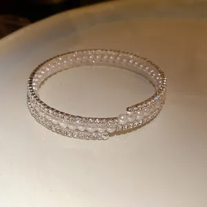 Dettaglio macro di un elegante bracciale a tre strati con perle e strass luccicanti.