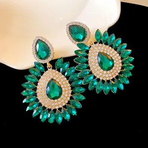 Close-up of exaggerated emerald green crystal flower earrings with sparkling rhinestones