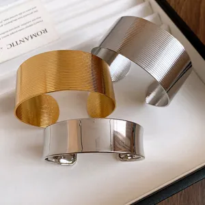 Detailed close-up of textured and smooth metallic wide open cuff bracelets for women