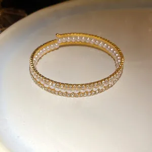 Primo piano di un bracciale aperto a tre strati con perle bianche e strass scintillanti