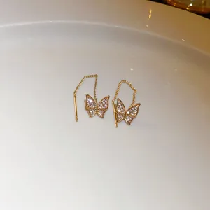 Elegant gold butterfly threader earrings with sparkling crystals on white ceramic