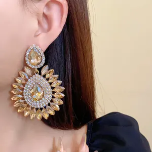 Exquisite detail view of oversized amber crystal flower drop earrings on a model ear