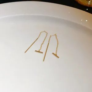 Close-up of minimalist 14k gold plated bar threader earrings on a white ceramic plate