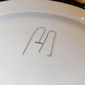 Detailed view of minimalist silver bar threader earrings on a white ceramic plate