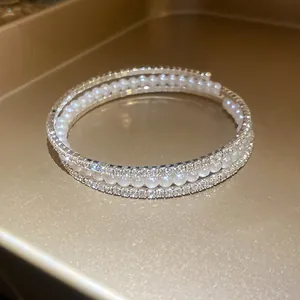 Dettaglio del bracciale a tre strati con strass scintillanti e eleganti perle bianche