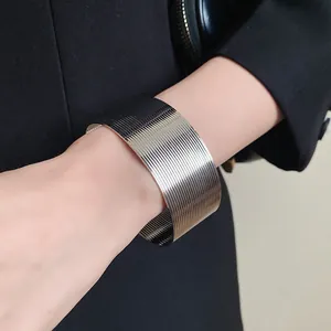Detail shot of a modern silver stainless steel wide cuff bracelet with ribbed texture