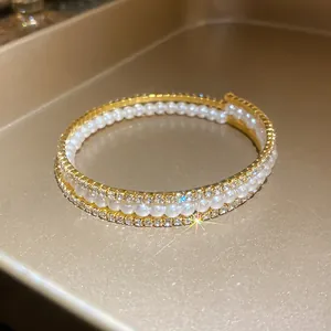 Dettaglio ravvicinato di un bracciale rigido a tre strati con perle e strass scintillanti