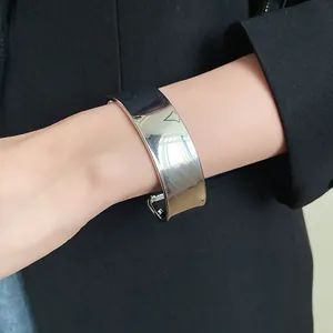 Close-up view of a minimalist wide polished stainless steel cuff bangle on a wrist