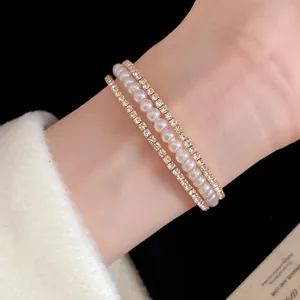 Primo piano di un bracciale aperto a tre strati di perle e strass indossato al polso.