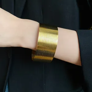 Close-up of a wide gold textured stainless steel open cuff bracelet on wrist.
