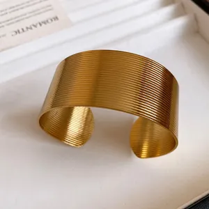 Close-up view of a gold stainless steel wide cuff bracelet with horizontal ribbed texture.