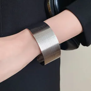Close-up of a textured silver stainless steel wide cuff bracelet on wrist.