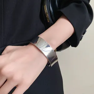 Close-up of minimalist stainless steel wide open cuff bracelet in silver finish.