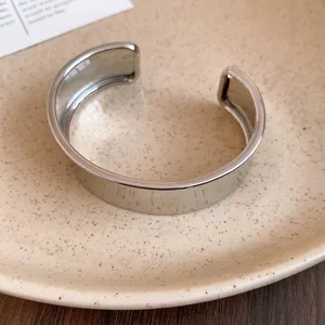 Close-up detail of a minimalist polished silver-colored wide open cuff bracelet