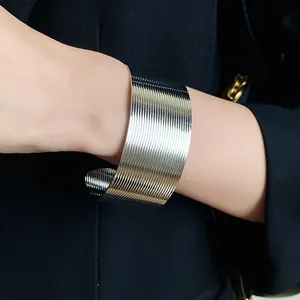 Detail view of a textured wide silver stainless steel cuff bracelet on a model's wrist