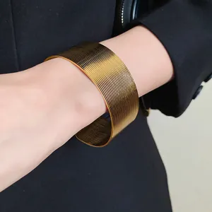 Macro detail of a textured wide gold stainless steel open cuff bracelet on a wrist