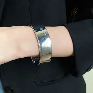 Detailed close-up shot showing a wide polished silver stainless steel cuff bangle on wrist