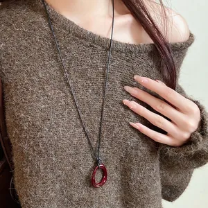 Retro irregular red resin geometric pendant necklace worn on a brown knit sweater