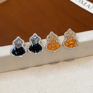 Dettaglio di orecchini a lobo a forma di zucca con zirconi scintillanti in nero e arancio