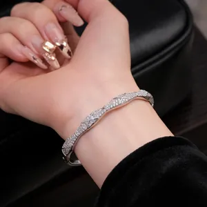 Gros plan d'un élégant jonc argenté croisé orné de zircons cubiques sur le poignet d'un mannequin