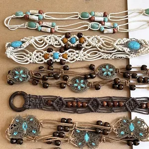 Detailed view of various bohemian woven waist chains featuring beads and metal flower charms