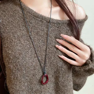 Close-up of a vintage red drip oil irregular geometric necklace on a brown sweater