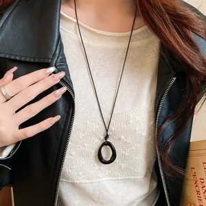 Detail shot of a black irregular geometric pendant necklace on a long black cord