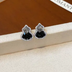 Primo piano di eleganti orecchini a zucca con pietre di zirconia cubica nere e chiare