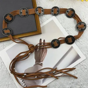 Detailed view of a brown Bohemian woven waist chain belt with metal medallions and tassels.