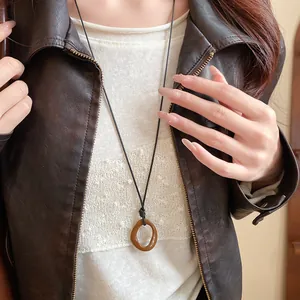 Close-up detail of a retro irregular geometric brown enamel necklace on a model