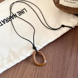 Detail view of a retro brown irregular geometric pendant on a minimalist black cord