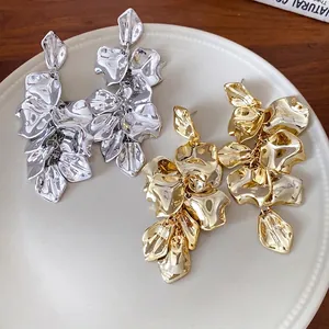 Pendientes vintage llamativos de flores de metal dorado y plateado en plato blanco