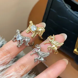 Macro view of gold and silver horse rings with heart-shaped zircon on fingers.